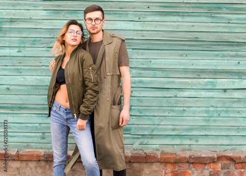 fashion couple standing posing near green wooden wall