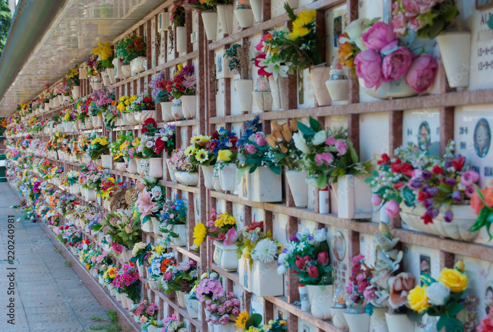Loculi of a cemetery with many colored plastic flowers
