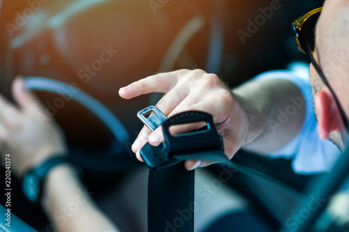 Male driver putting on a seat belt. Man fastening car seat belt. Unrecognizable person, natural lighting