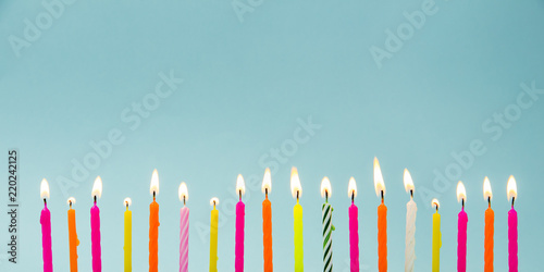 Fotobehang Set of many different color shape and pattern birthday candles burning in long row, isolated on blue
