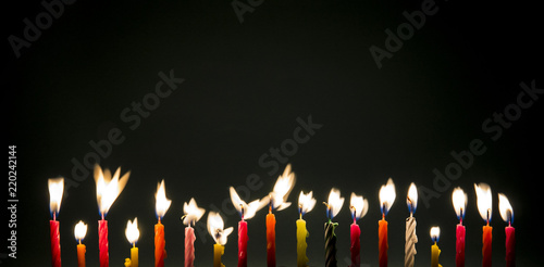 Wall Mural Set of many different color shape and pattern birthday candles burning flames in motion, long exposure in dark isolated on black