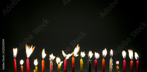 Set of many different color shape and pattern birthday candles burning flames in motion, long exposure in dark isolated on black. Happy Birthday card design concept. 