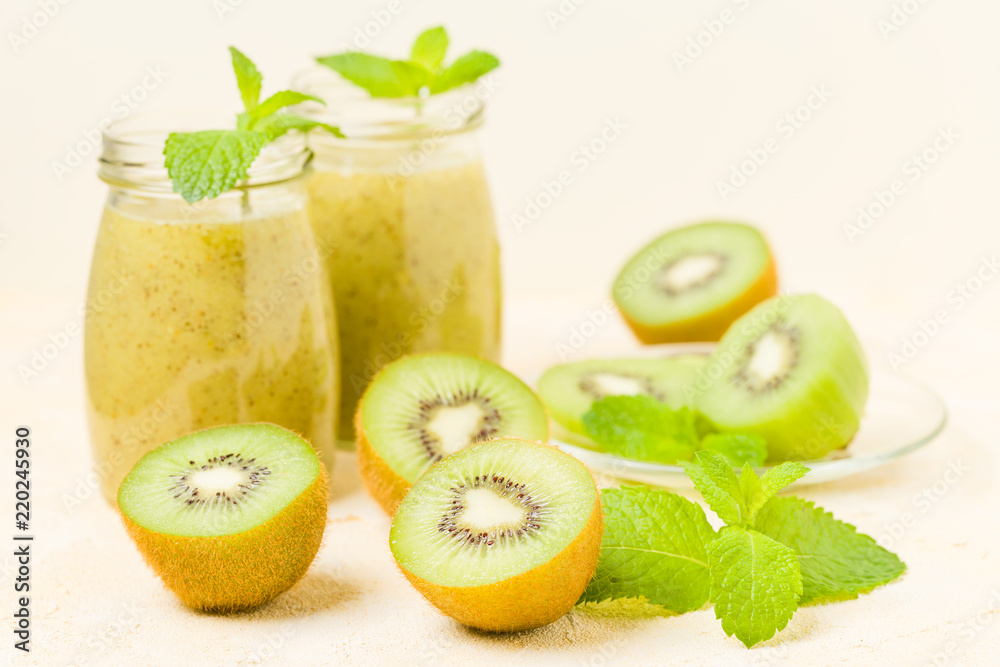 Kiwi smoothie decorated with fresh green mint leaves and raw ripe cut fruit on yellow pastel background. Kiwi smoothie decorated with fresh green mint leaves and raw ripe cut fruit on yellow pastel background.