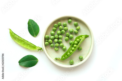 Isolated sweet green peas on plate. Top view. White background. Open beans pod. 