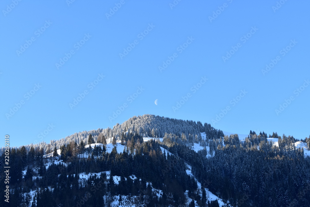 Moon going down over an alpine mountain