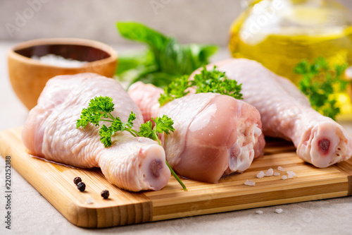 Raw chicken legs with spices and herbs on cutting board