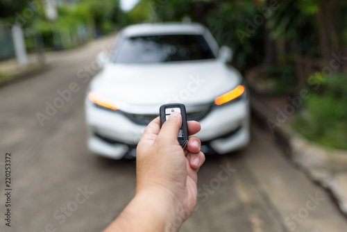 A man's hand is pressing the remote to lock or unlock the car door.