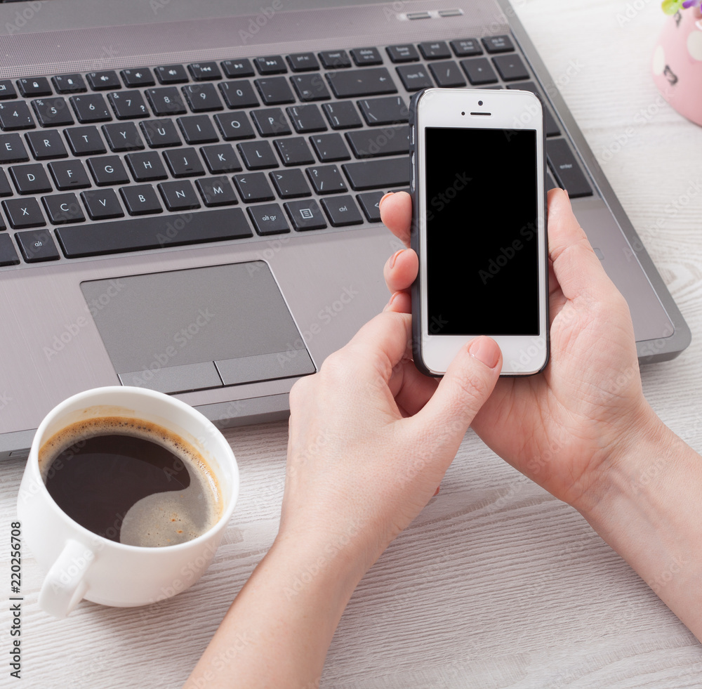 Woman holds smartphone white phone in the workplace in the room. Woman using a mobile phone for work.