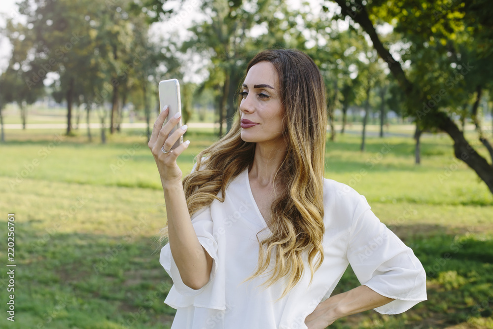 Portrait of young woman making selfie photo in park Portrait of young woman making selfie photo in park