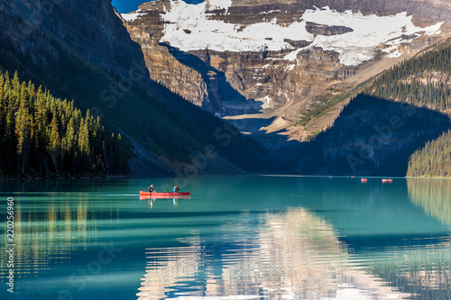 Banff, Canada - Ago 19th 2017 - Tourists doing kayak and enjoying the amazing scenario of lake Moraine, early morning light, glacial at the background, blue sky in summer time Banff. photo