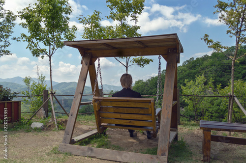 rear view of man sitting on wooden swing