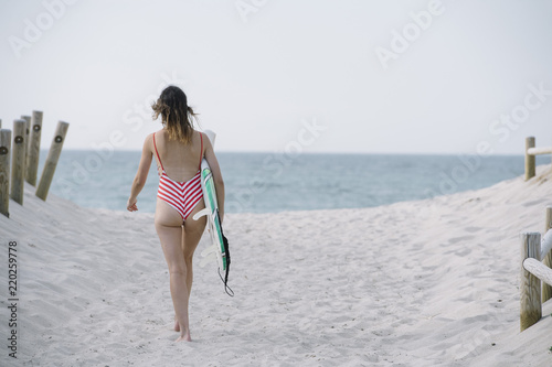 Portrait of a surfer woman on a beach holding a surfboard