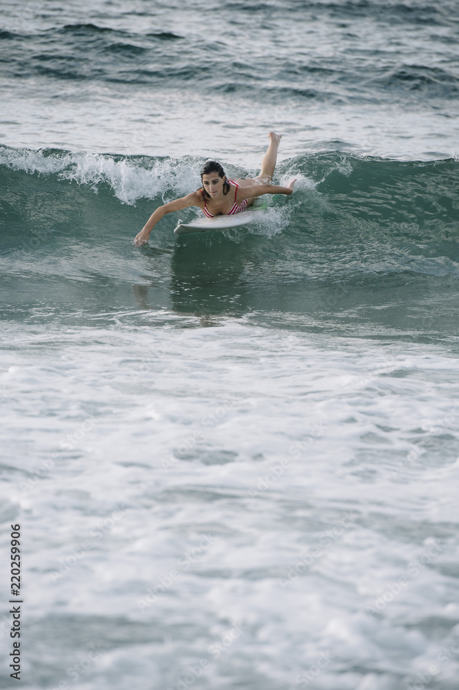Young woman surfing the wave on his surfboard