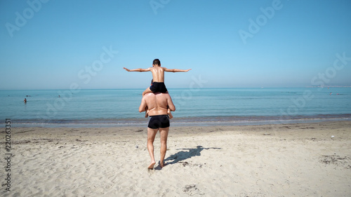 Father and Son Play Airplane Arms Raised Together at the Beach. Happy Fun Smiling Lifestyle