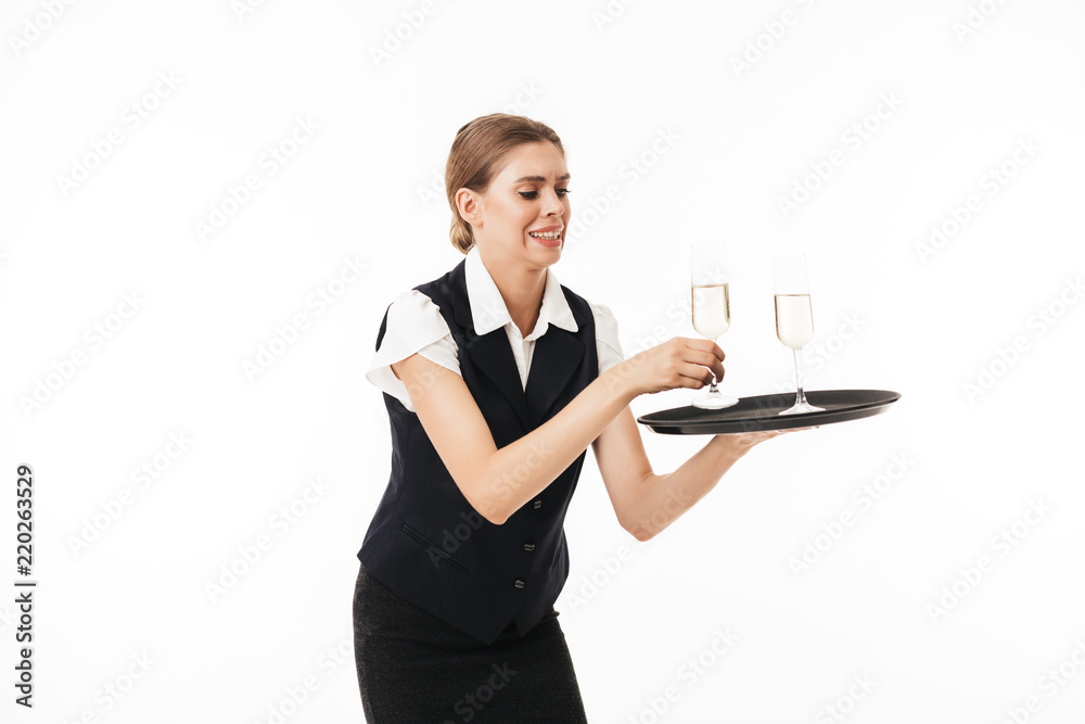 Young waitress in uniform trying to hold tray with glasses over white background Young waitress in uniform trying to hold tray with glasses over white background