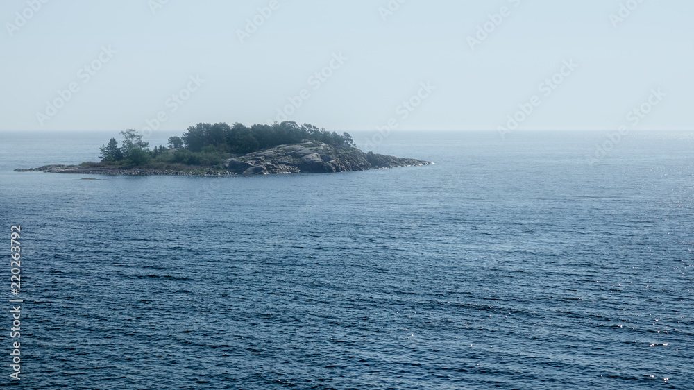 Lonely rocky island in endless ocean.