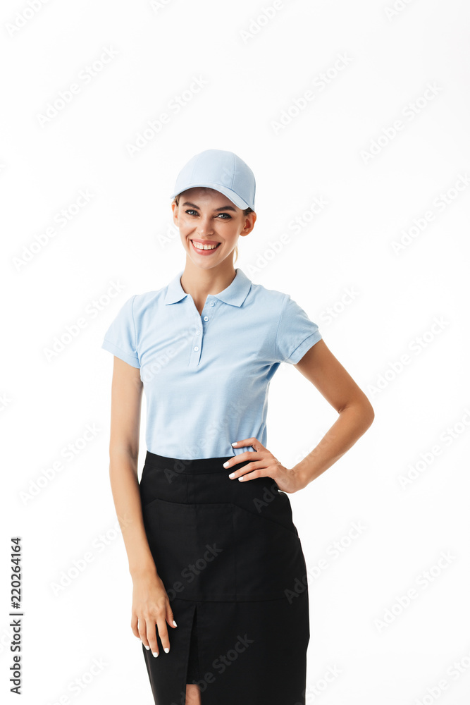 Pretty girl in blue polo T-shirt and cap joyfully looking in camera over white background isolated
