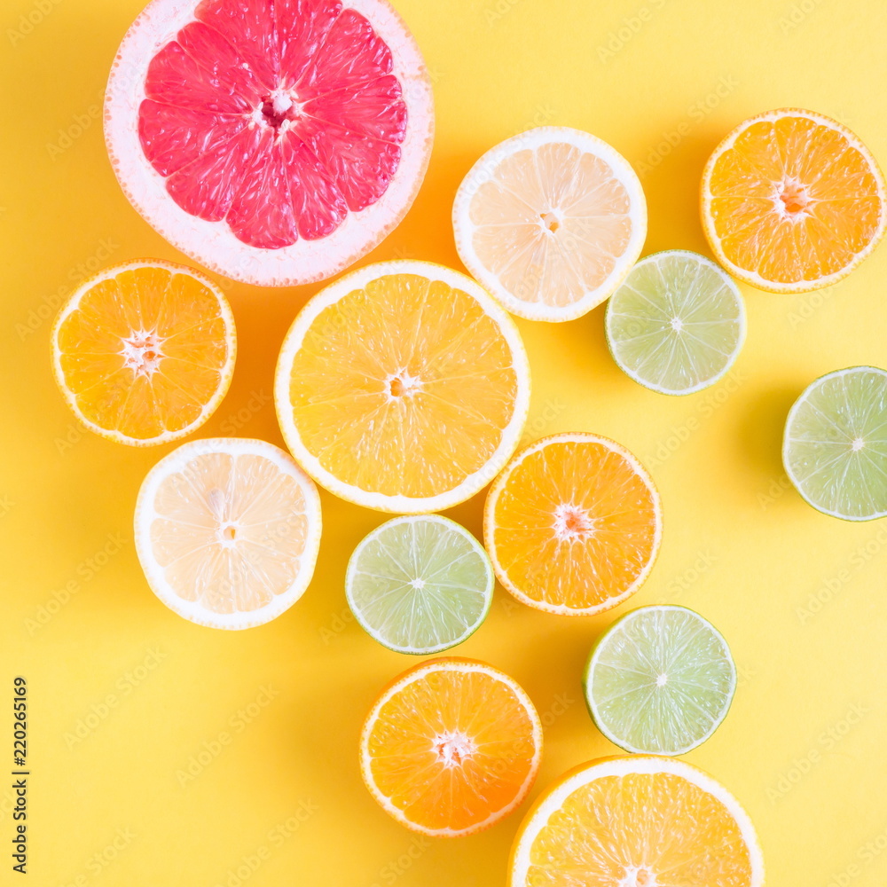 Creative background made of summer tropical fruits, grapefruit, orange, tangerine, lemon, lime on pastel yellow background. Food concept. Flat lay, top view, copy space 