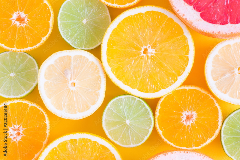 Creative background made of summer tropical fruits, grapefruit, orange, tangerine, lemon, lime on pastel yellow background. Food concept. Flat lay, top view, copy space 