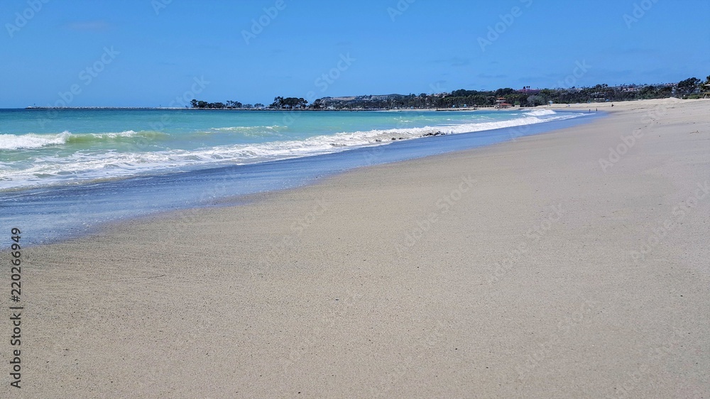 Beautiful empty sandy beach with vibrant blue ocean waves.