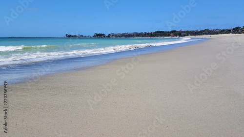 Beautiful empty sandy beach with vibrant blue ocean waves.