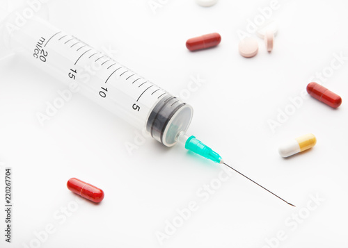 Needle syringe and pills on white background.