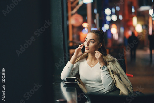 girl sitting outside a cafe using her phone © prostooleh