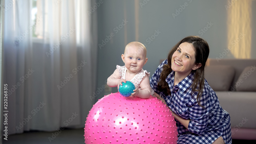Happy mother and cute baby girl smiling at camera, playing with balls at home Happy mother and cute baby girl smiling at camera, playing with balls at home