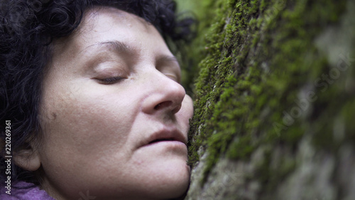 Emotional woman resting on the nature hand touching the stone moss in forest. Beautiful girl lying on the field. perfect for commercial or video clip