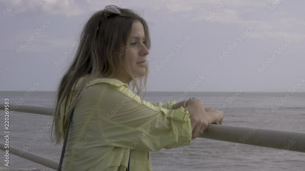 Pretty young lady with a thoughtful expression looks out to sea Pretty young lady with a thoughtful expression looks out to sea