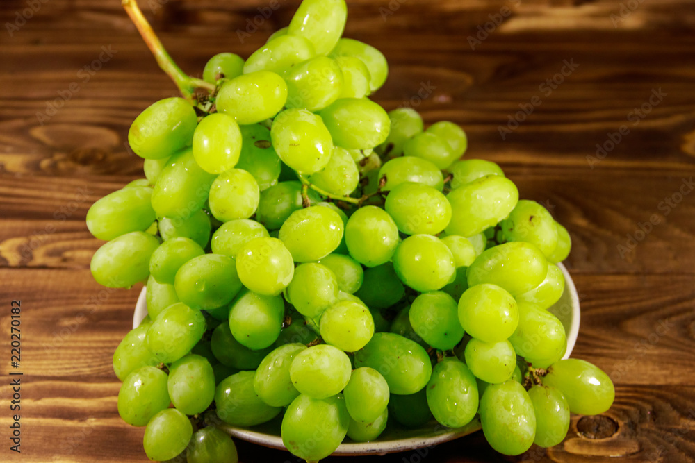 Tasty fresh white grape in a plate on wooden table Tasty fresh white grape in a plate on wooden table