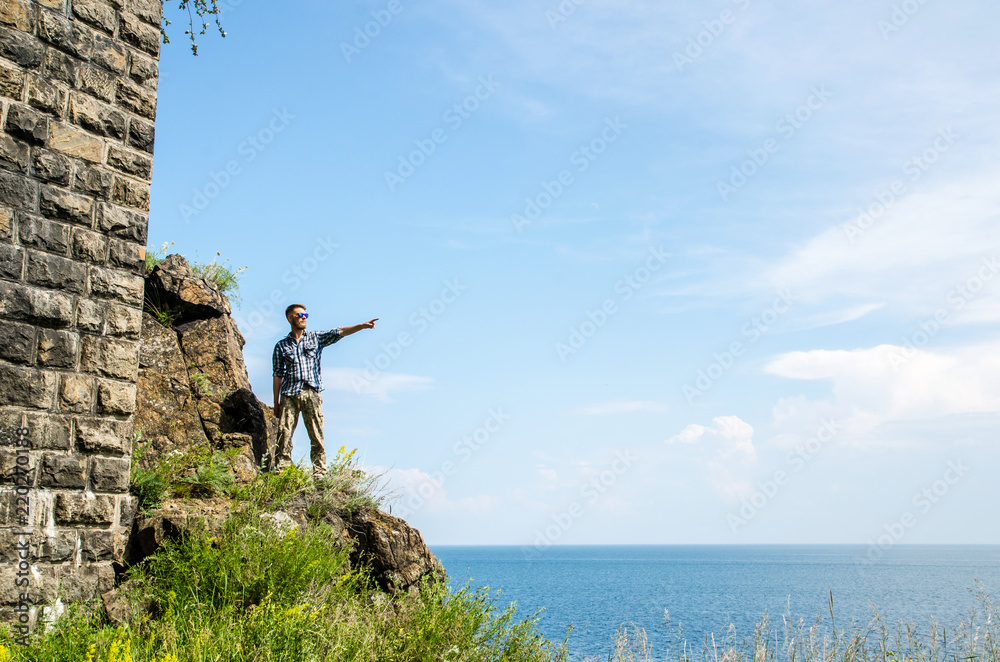 Young tourist with beard stays on a mountain with tunnel on a lake background.