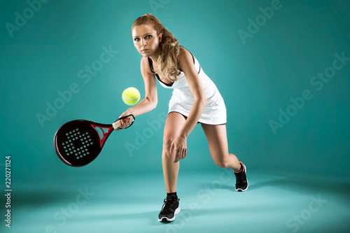 Foto Pretty young woman playing padel indoor over green-blue background