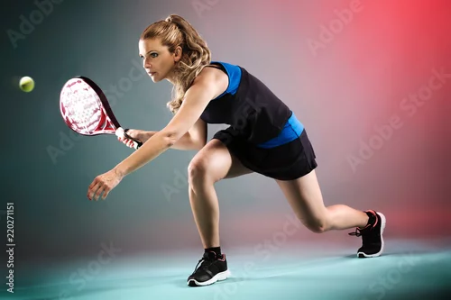 Obraz Piękna młoda kobieta bawić się padel salowego nad stubarwnym tłem.