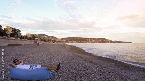 Man resting and enjoying view of Mediterranean Sea lying on air sofa on coast