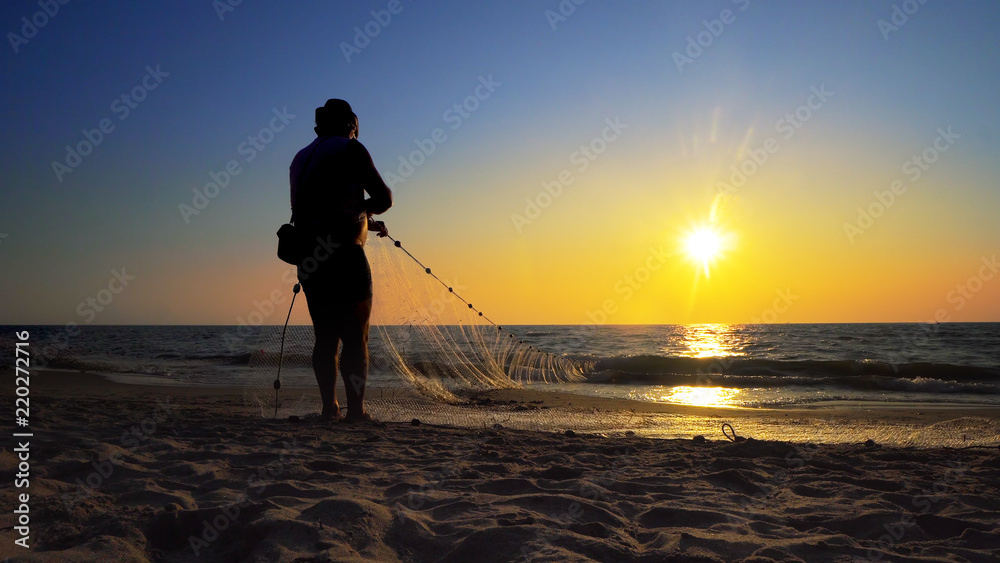 Coast Fishermen fishing hand pulling net at sunset on ocean coast