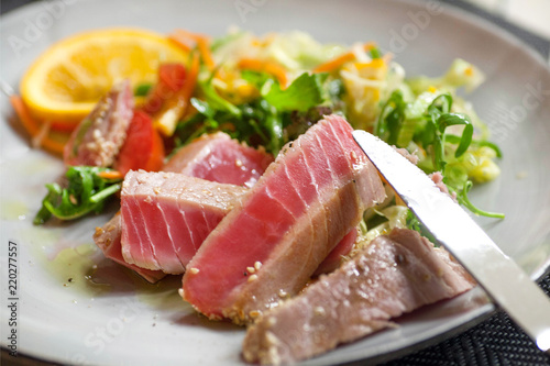 Food of mediterranian restaurant. Fish tuna meat dish on plate with orange and vegetables photo