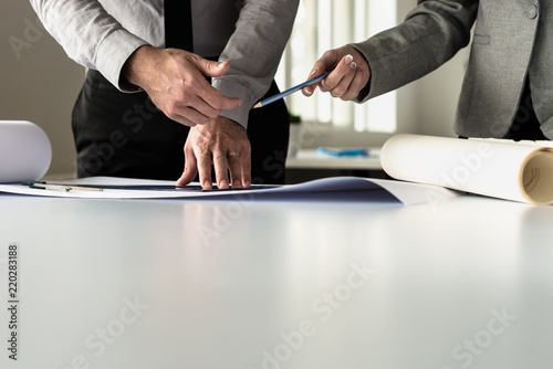 Businessman hands offer pencil to architect working on plans photo