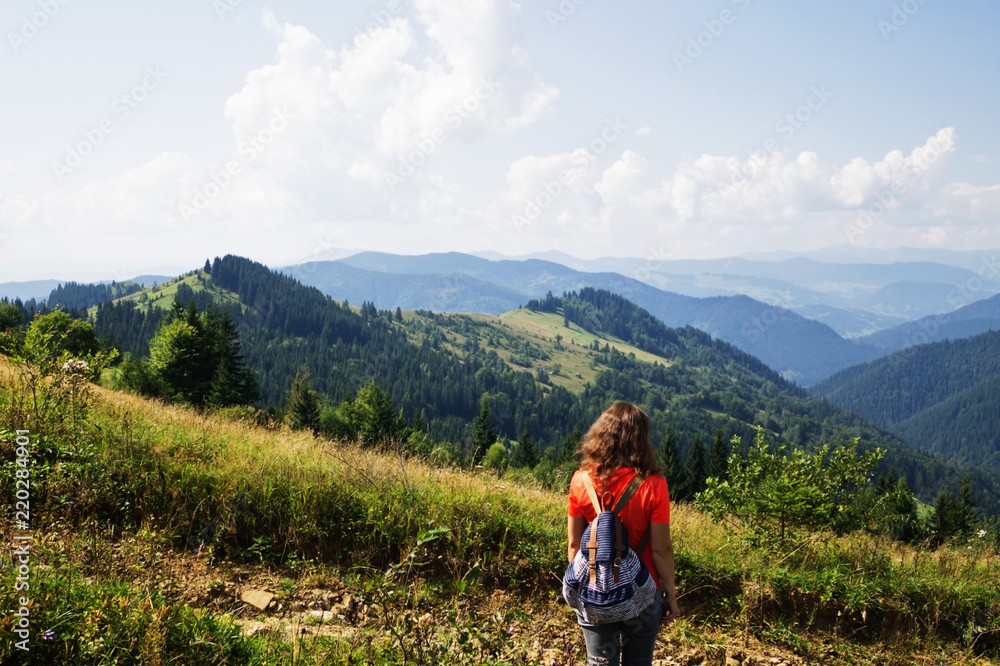 Girl in the mountains, a traveler photographed from the back