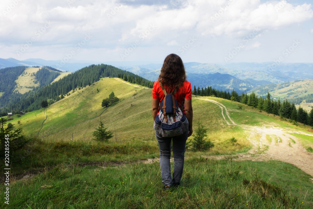 Girl in the mountains, a traveler photographed from the back