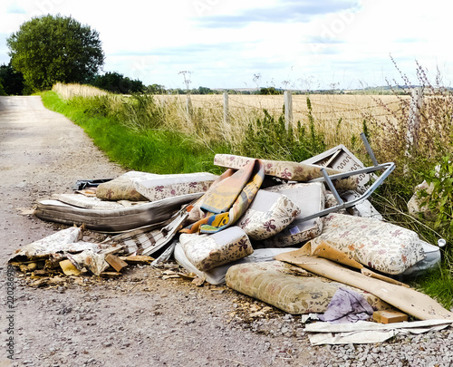 Heap of illegally dumped household rubbish left in a little used country lane. Environmental hazard, with furniture. mattresses and carpets. Fly tipped detritus. Oxfordshire.