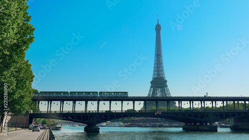 Paris, France - circa May, 2017: World Famous Structure Eiffel Tower and Bir-Hakeim Bridge with Subway Metro Train Passing Busy City and road traffic