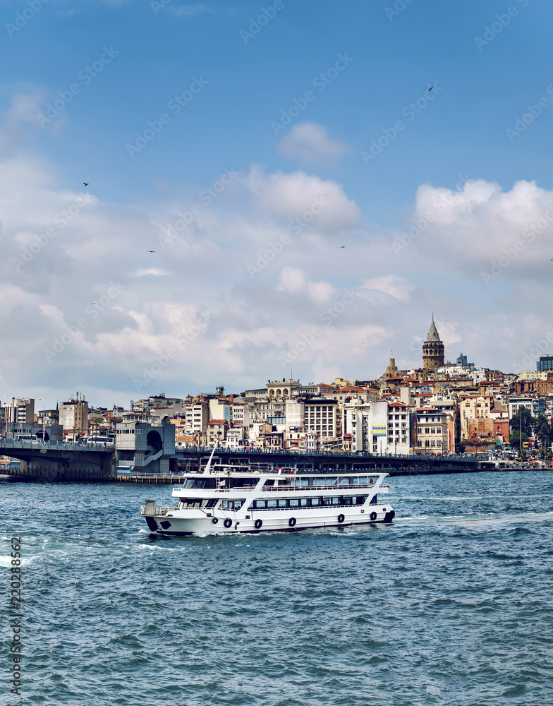 Istanbul, Tourist boat at Galata bridge with view of Galata tower to Golden Horn at background, Turkey