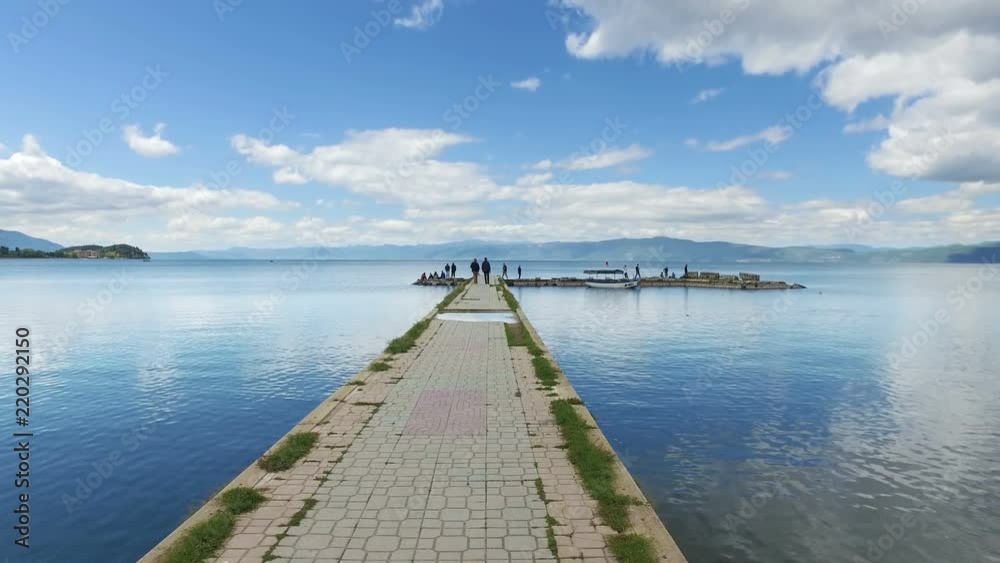 Moving on fishermans port on Ohrid lake with calm water reflection and blue sky Moving on fishermans port on Ohrid lake with calm water reflection and blue sky
