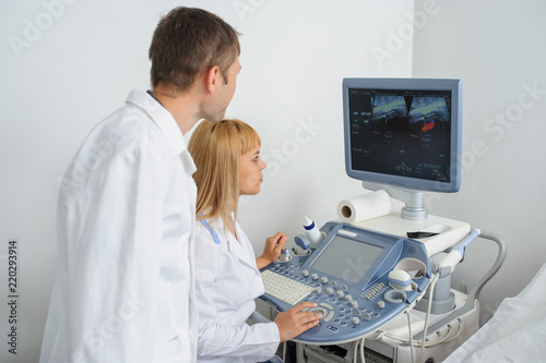 Two doctors looking at the ultrasonography divice