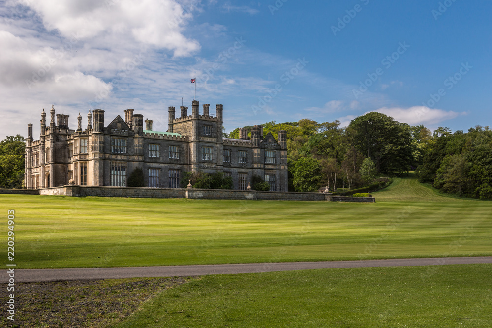 Edinburgh, Scotland, UK - June 14, 2012: Dalmany house, mansion and castle in Tudor revival style with the trees and its park in the back. Blue sky.