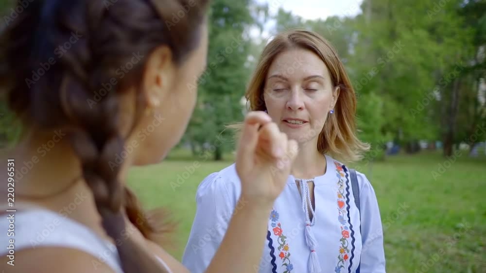 ginger head woman is talking with her female friend in a park in summer evening, listening to her ginger head woman is talking with her female friend in a park in summer evening, listening to her