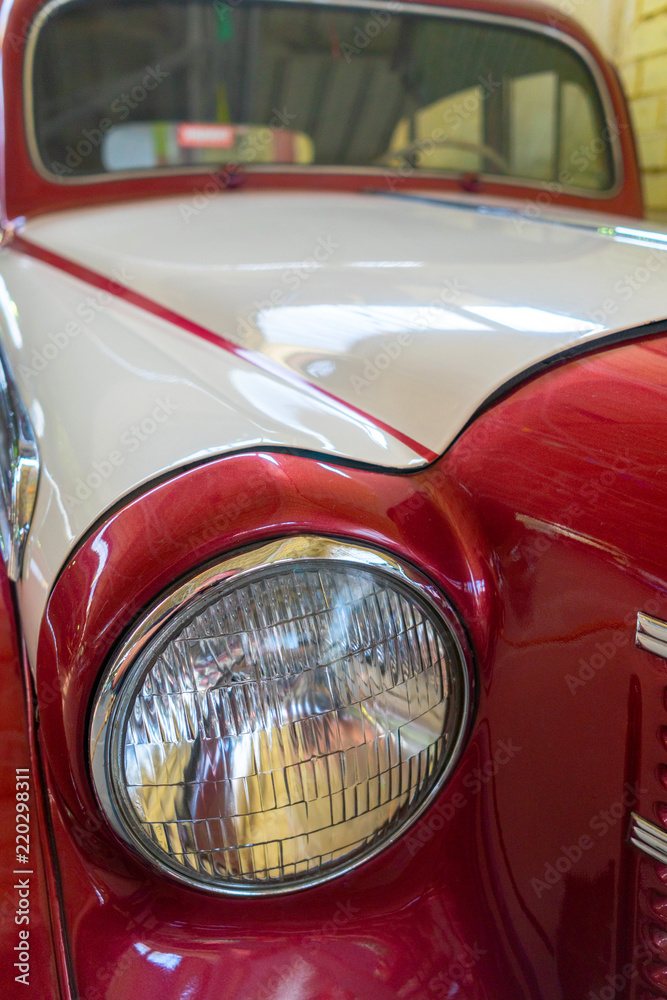 The headlight of a red antique, rarity, vintage car.