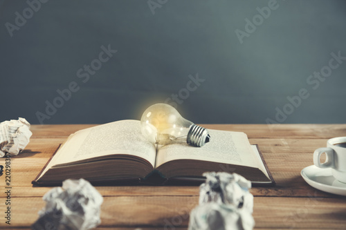 light bulb on vintage book with crumpled papers