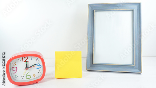 Blue wooden frame with red clock time 12.15 am. and note pad yellow on white background,copy space. . photo